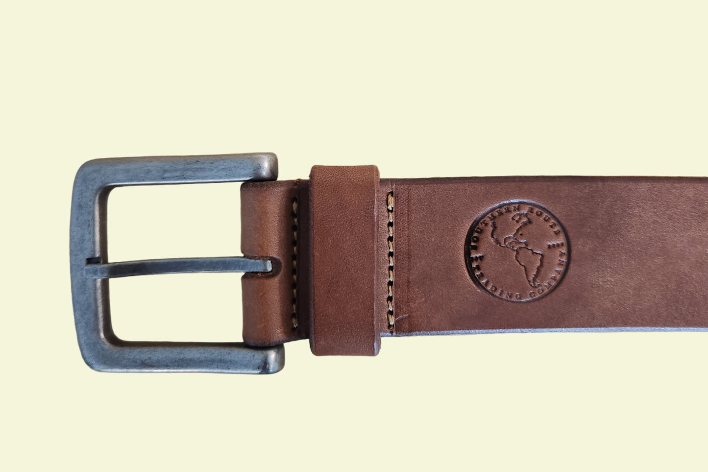 Brown leather belt with metal buckle on a wooden surface