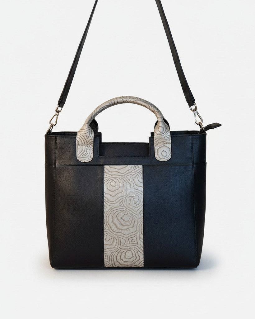 Black handbag with patterned handles on a beige background