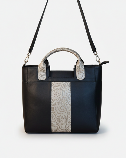 Black handbag with patterned handles on a beige background