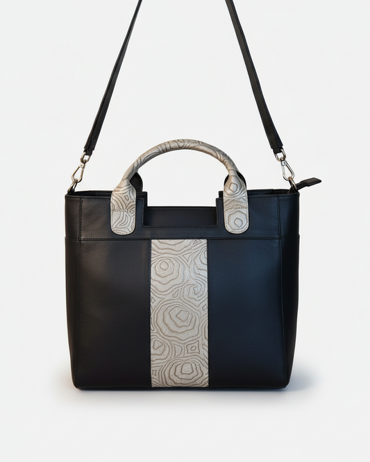 Black handbag with patterned handles on a beige background