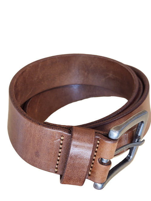 Brown leather belt with a silver buckle on a beige background