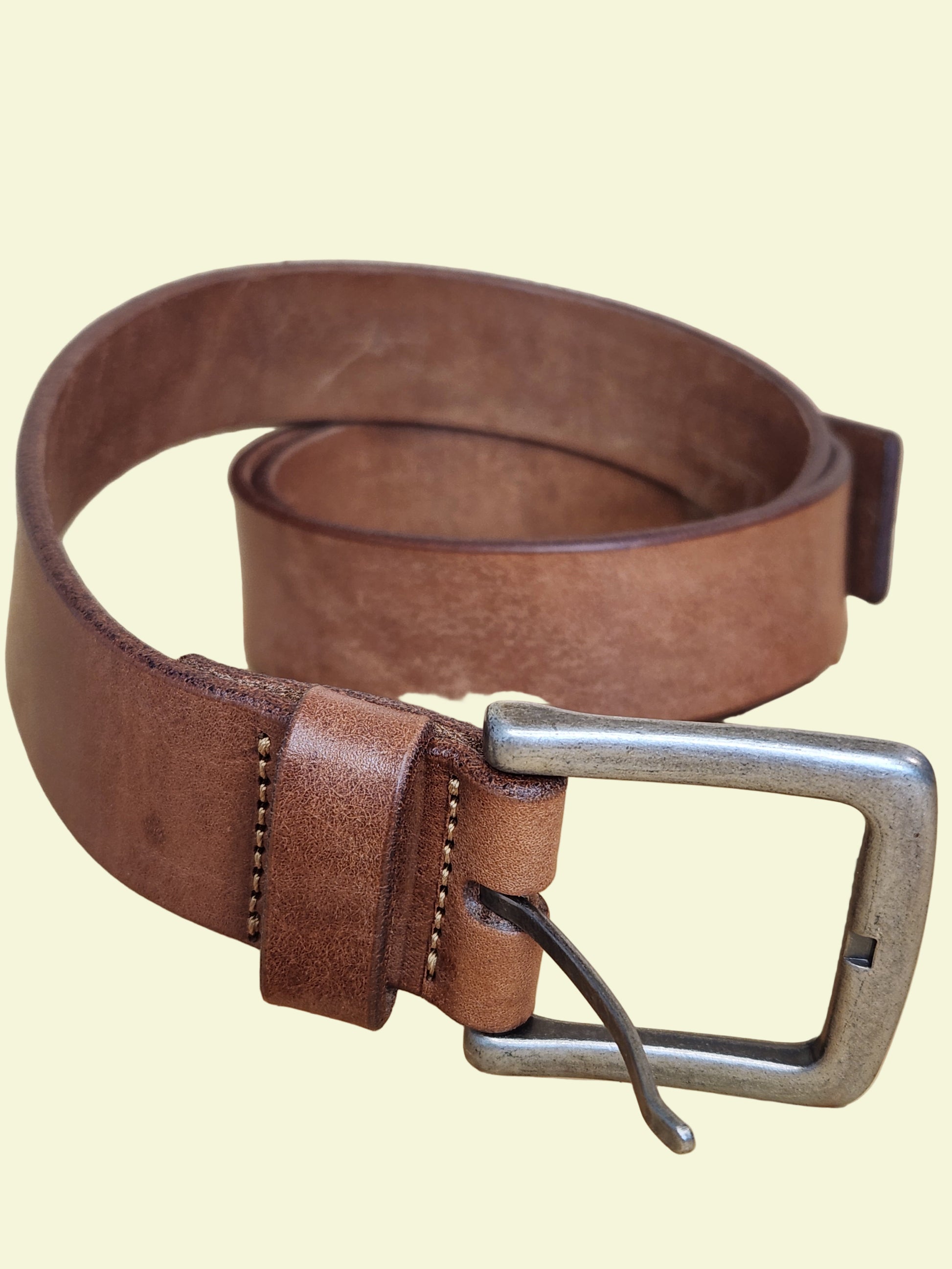 Brown leather belt with a silver buckle on a wooden surface
