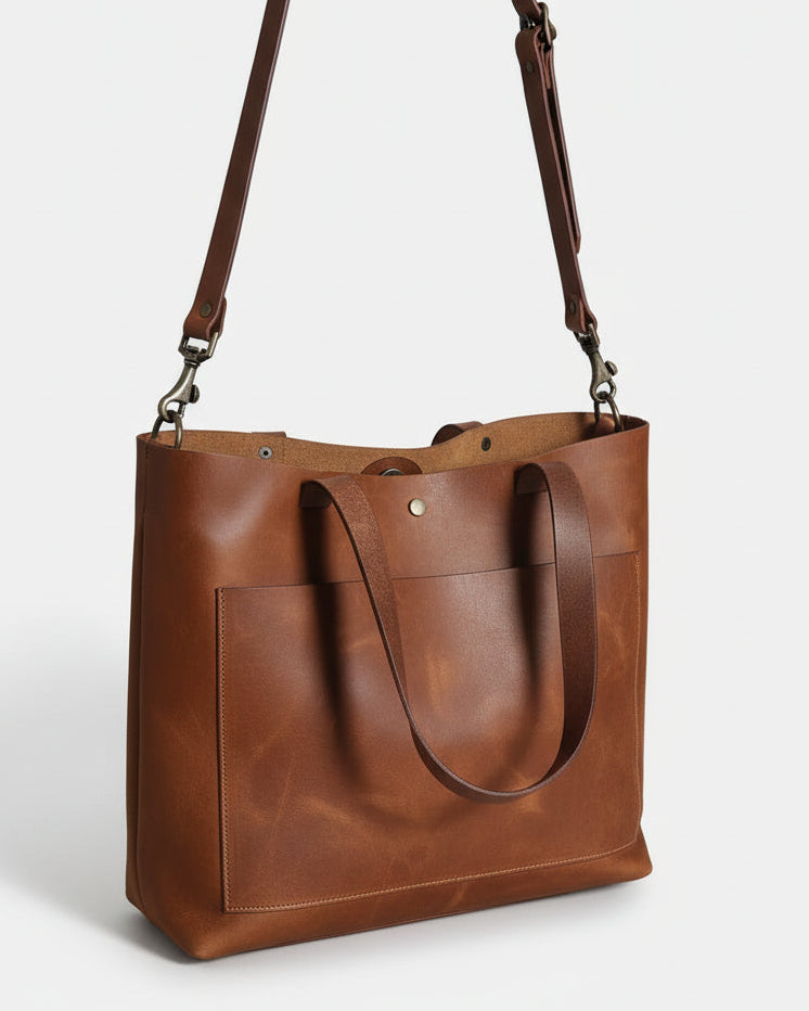 Brown leather bag with a strap on a wooden surface