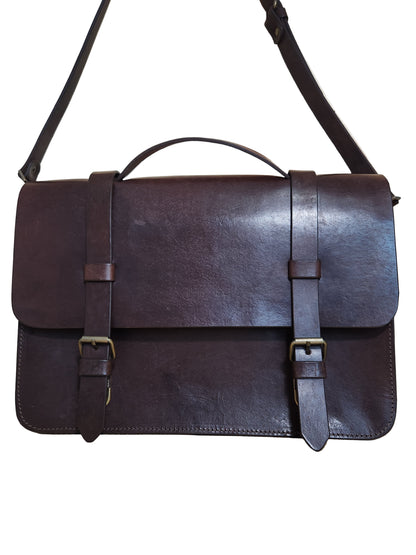 Brown leather bag with straps on a wooden surface