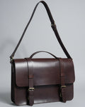 Brown leather bag with straps on a wooden surface