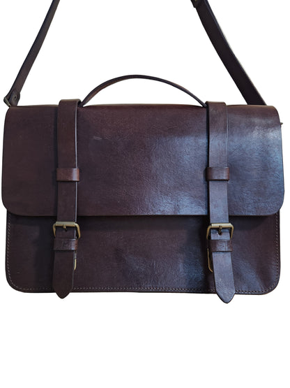Brown leather bag with straps on a wooden surface