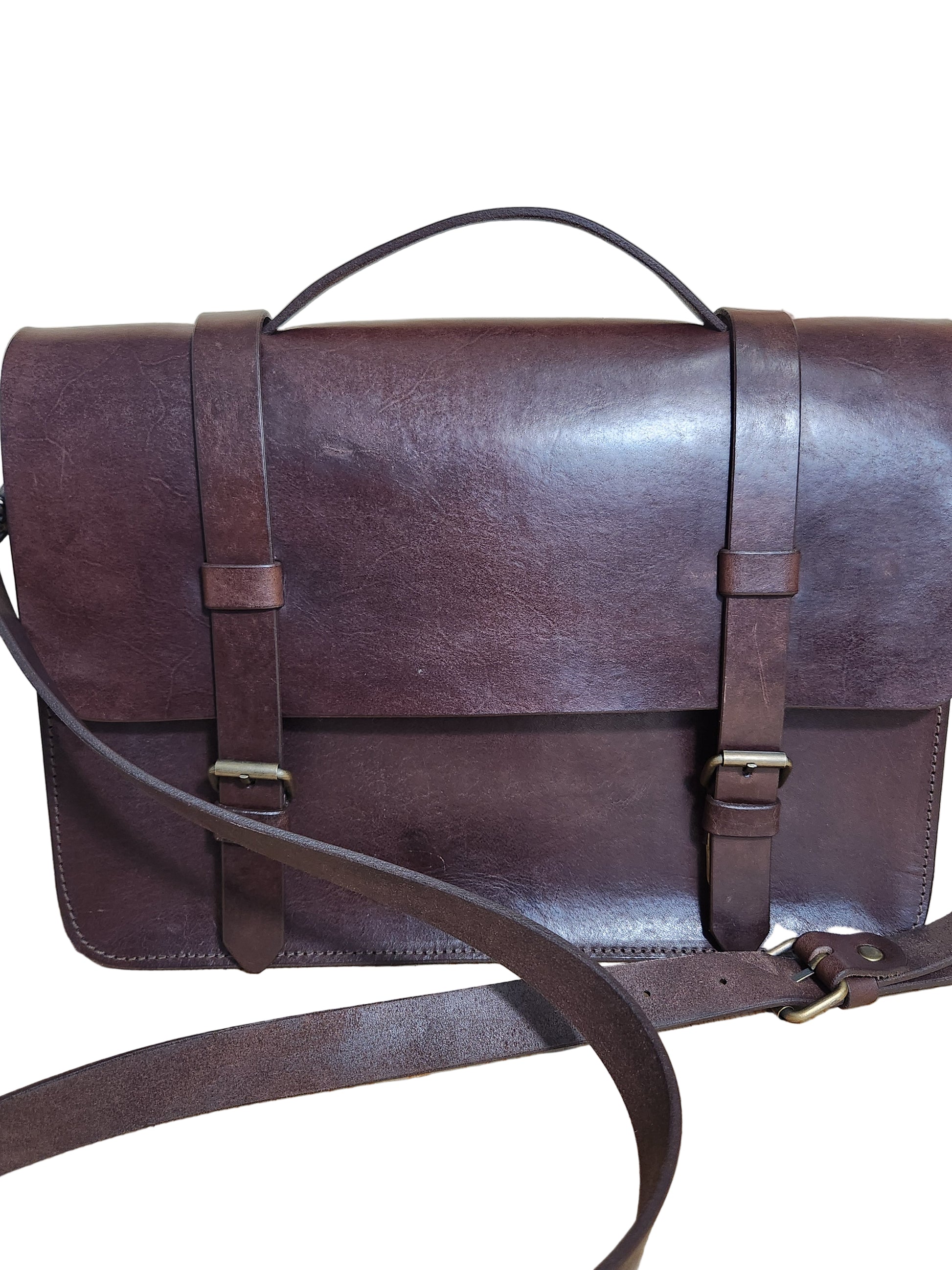 Brown leather bag with straps on a wooden surface