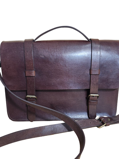 Brown leather bag with straps on a wooden surface