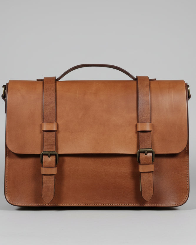 Brown leather bag with straps on a wooden surface