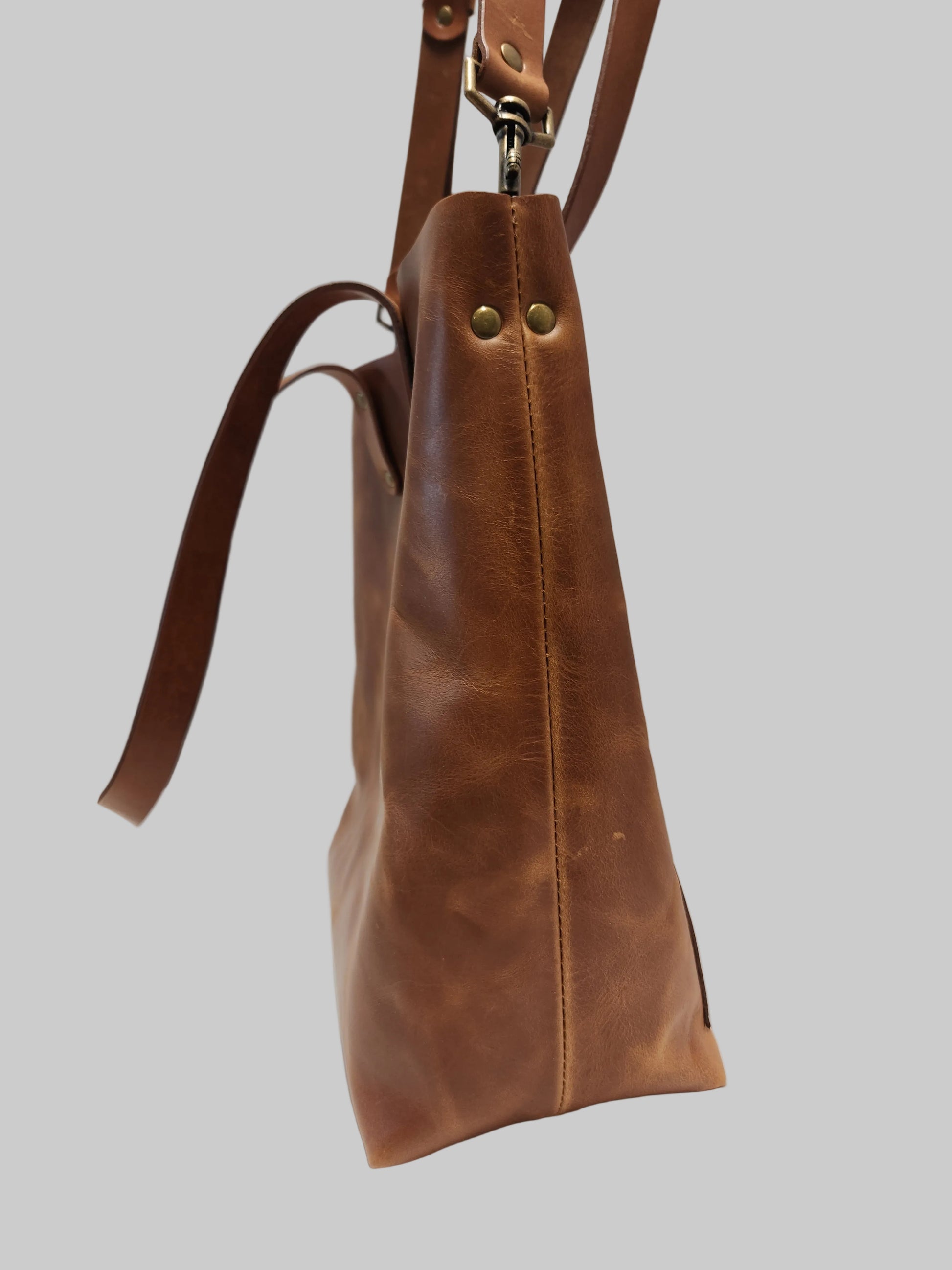 Brown leather handbag with gold hardware on a light gray background