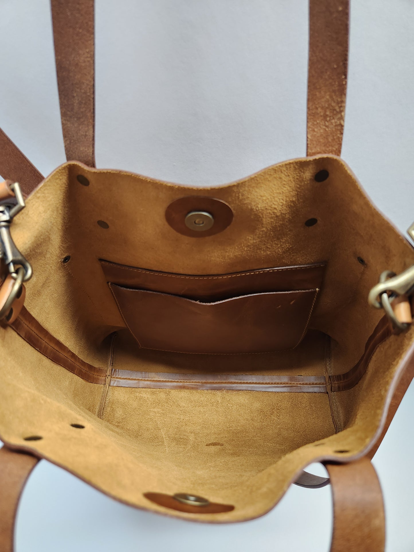 Close-up of a brown leather bag with visible stitching on a light gray background