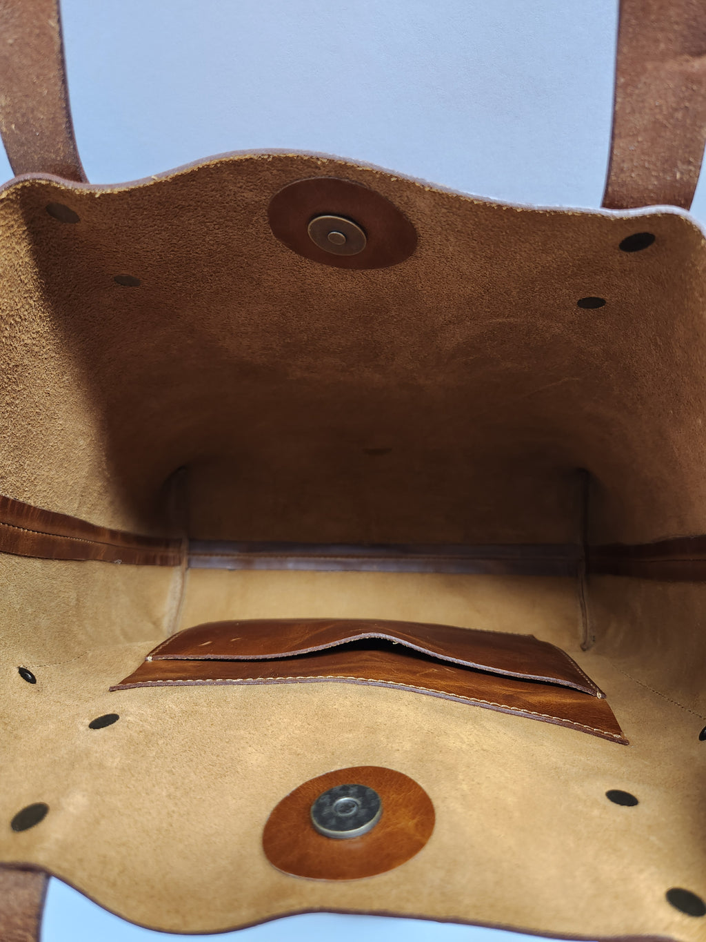Close-up of a brown leather bag with stitching details on a light blue background