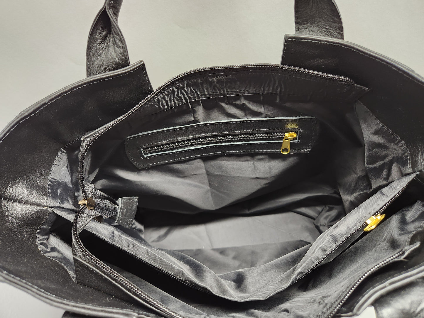 Black leather bag with open interior showing a checkered pattern.