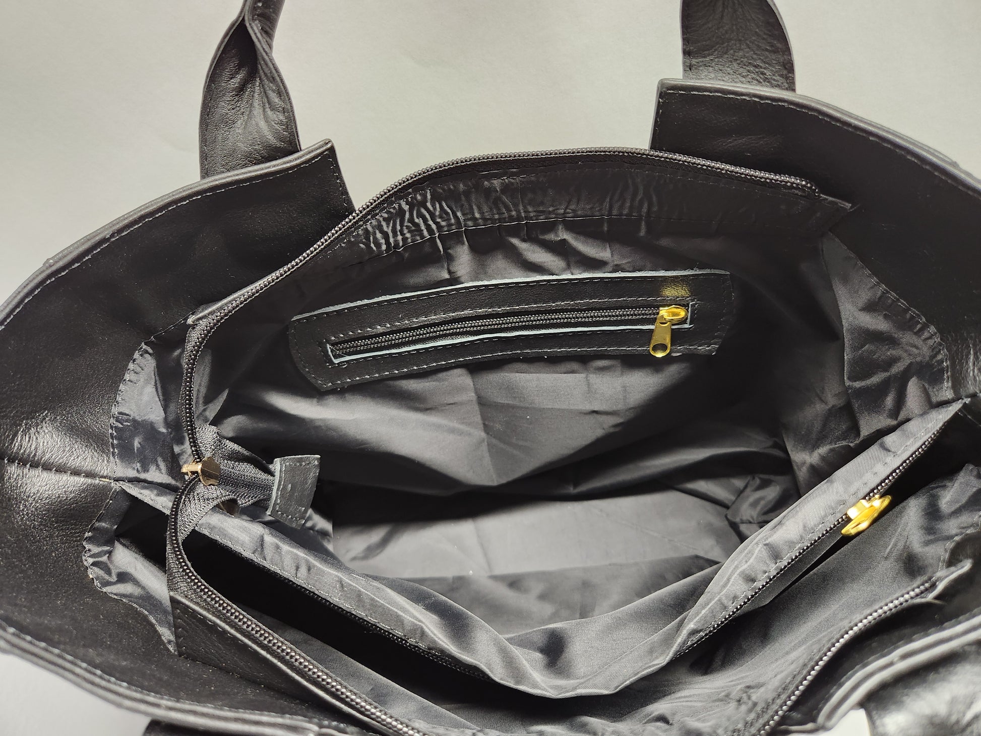 Black leather bag with open interior showing a checkered pattern.