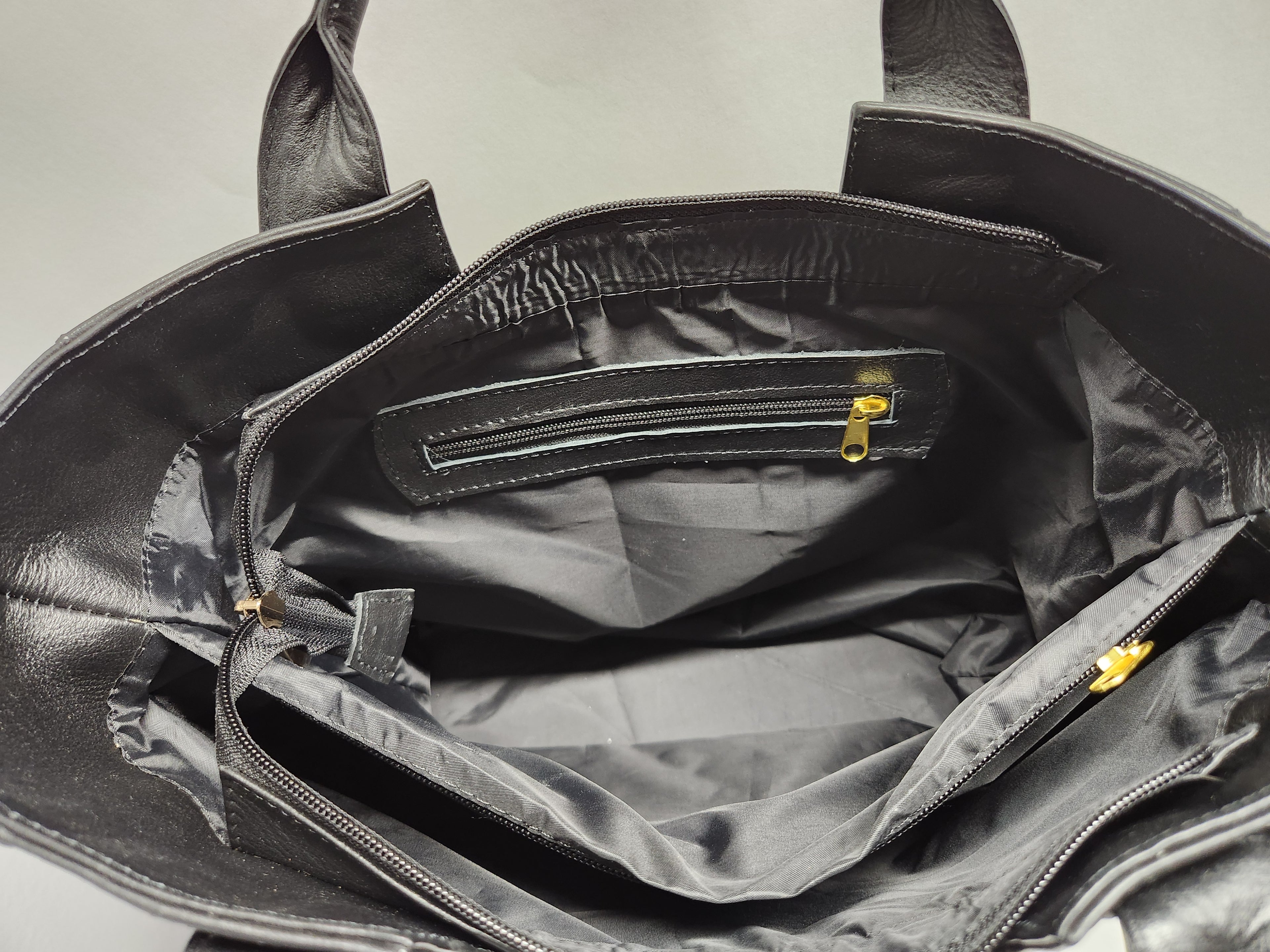 Black leather bag with open interior showing a checkered pattern.