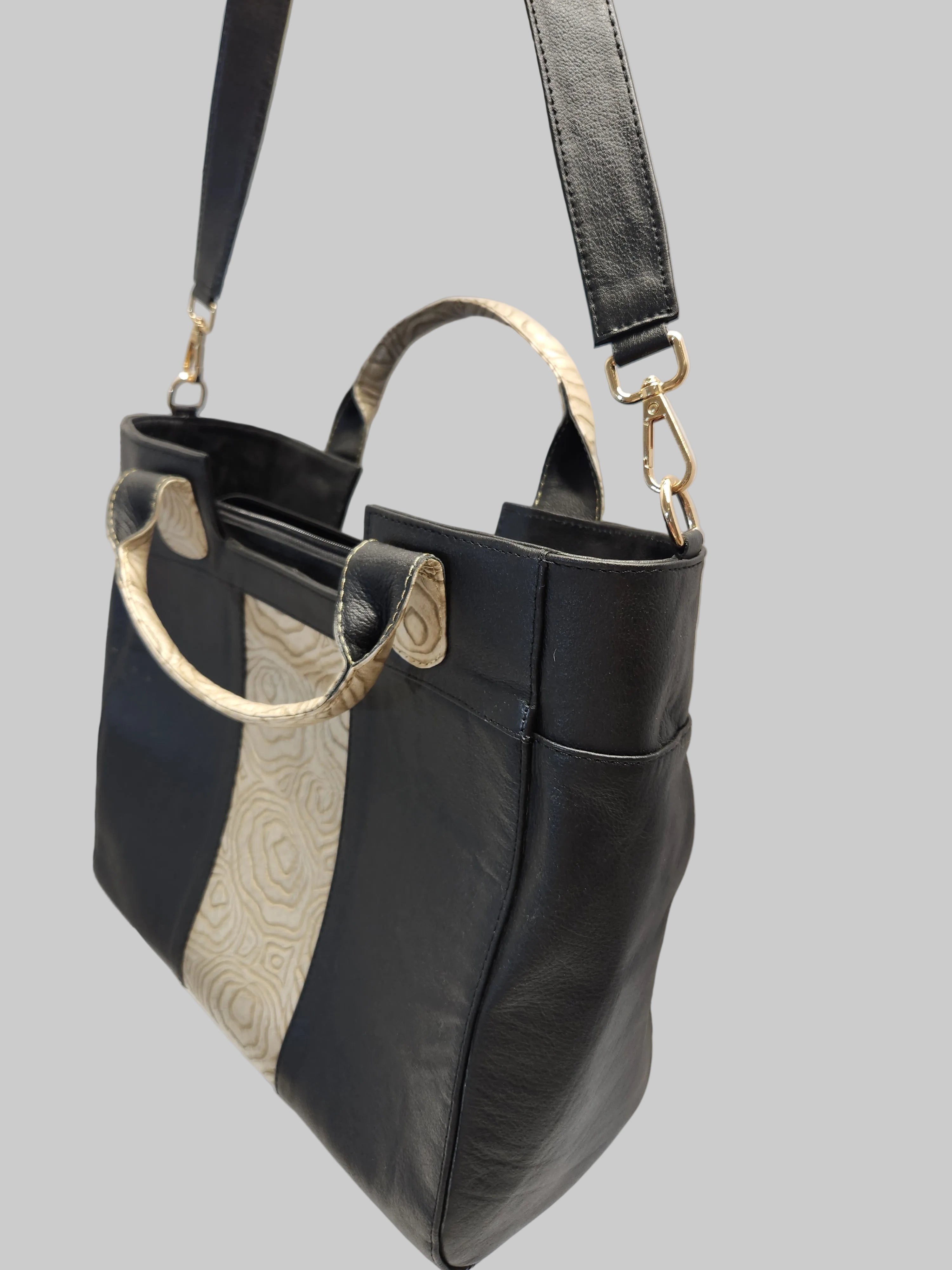 Black leather handbag with gold accents on a white background
