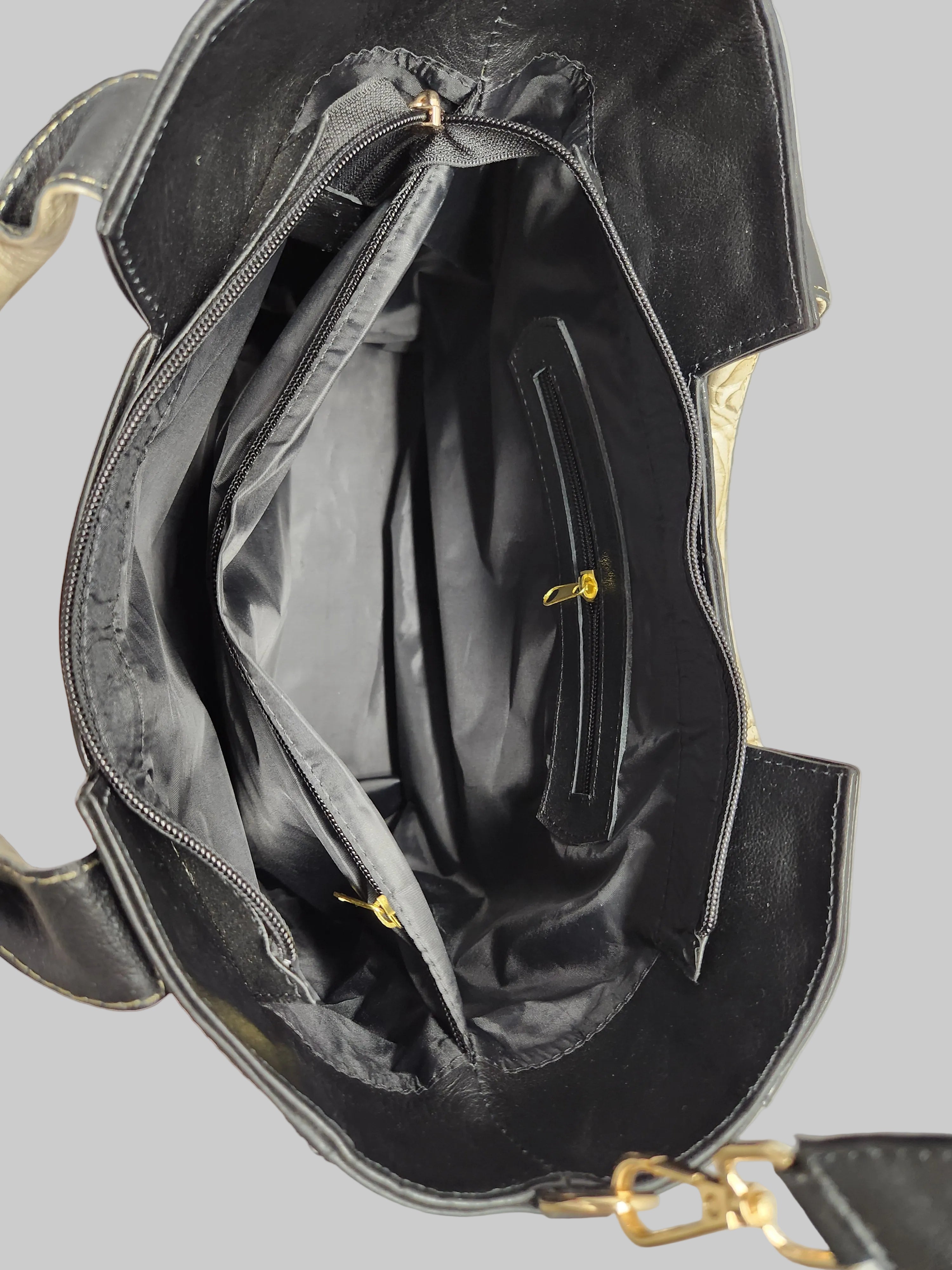 Black handbag with gold accents on a light gray background