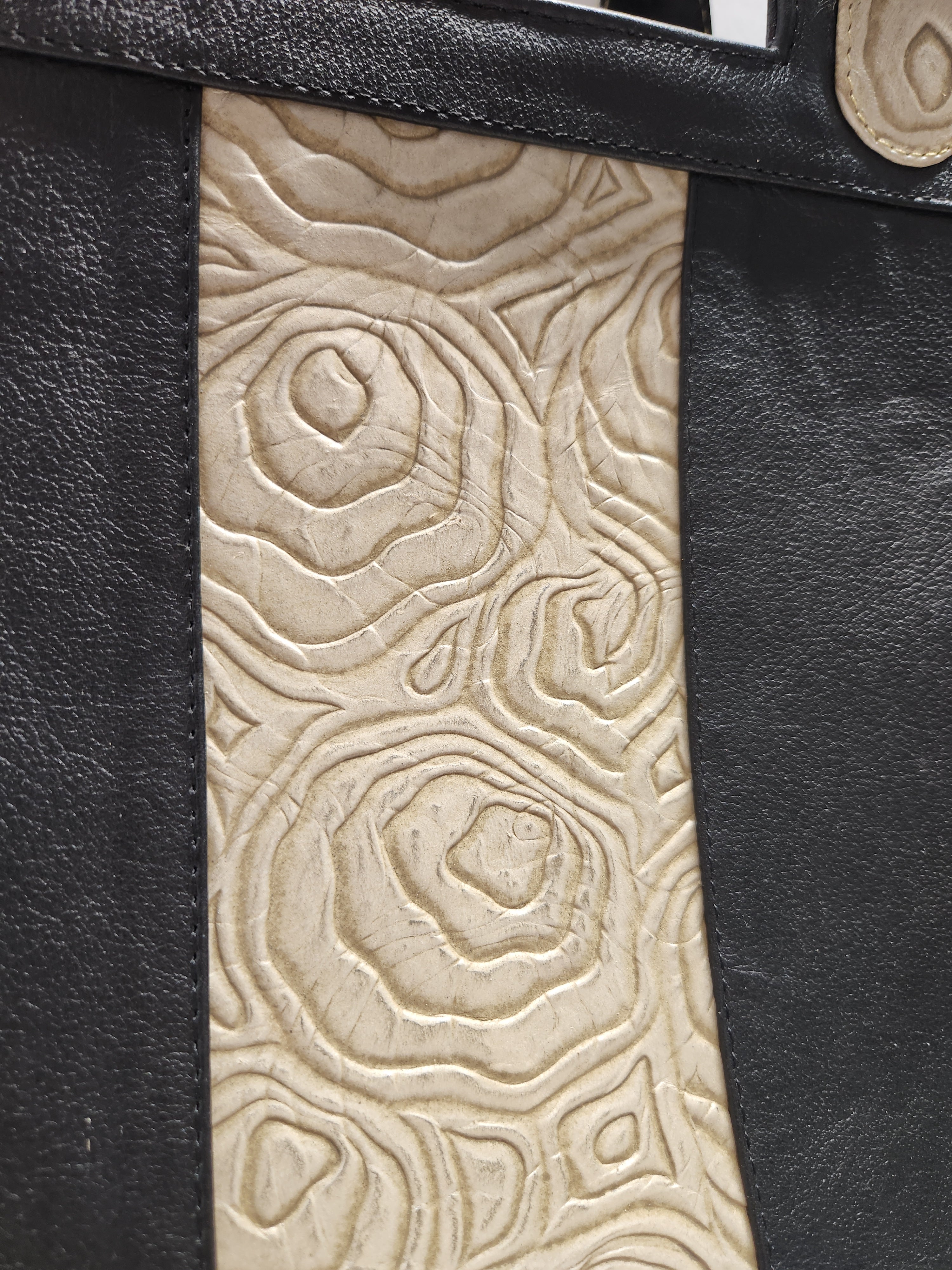 Close-up of a black leather product with embossed beige pattern