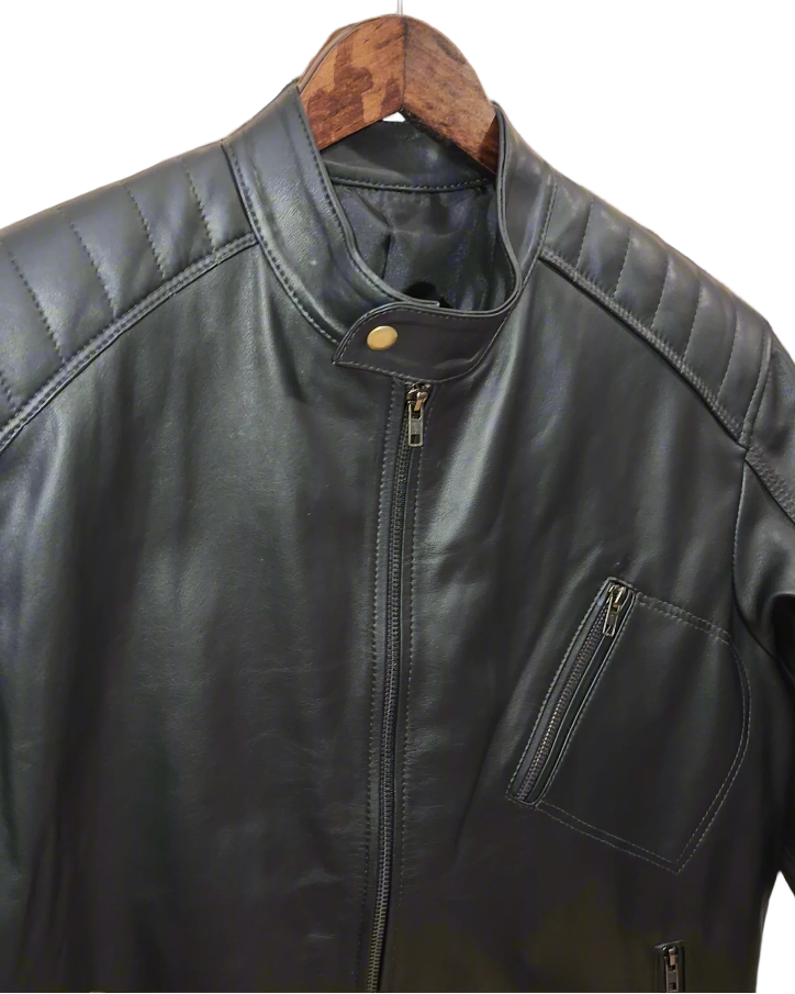 Black leather jacket on a wooden hanger against a brick wall.