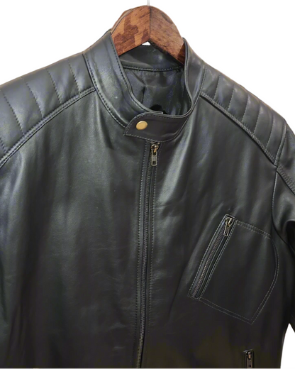 Black leather jacket on a wooden hanger against a brick wall.