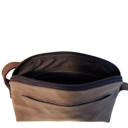 Brown leather pouch with a zipper on a wooden surface