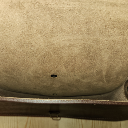 Close-up of a textured beige surface with a small black object on a wooden floor.