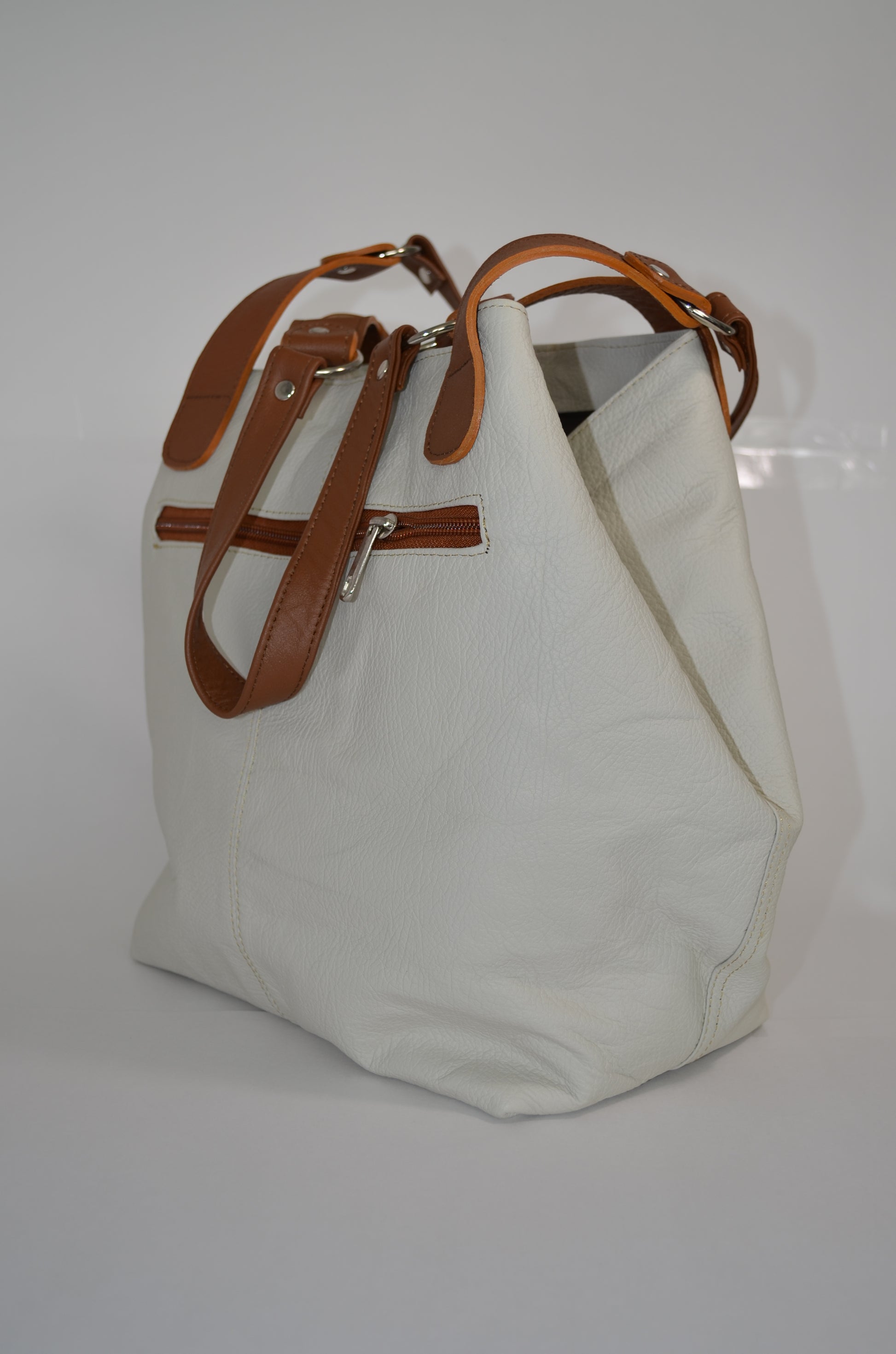 White tote bag with brown leather straps on a white background
