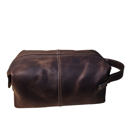 Brown leather toiletry bag on a beige background