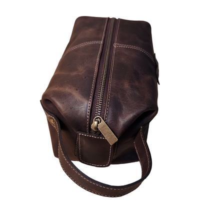 Brown leather bag with a zipper on a wooden surface