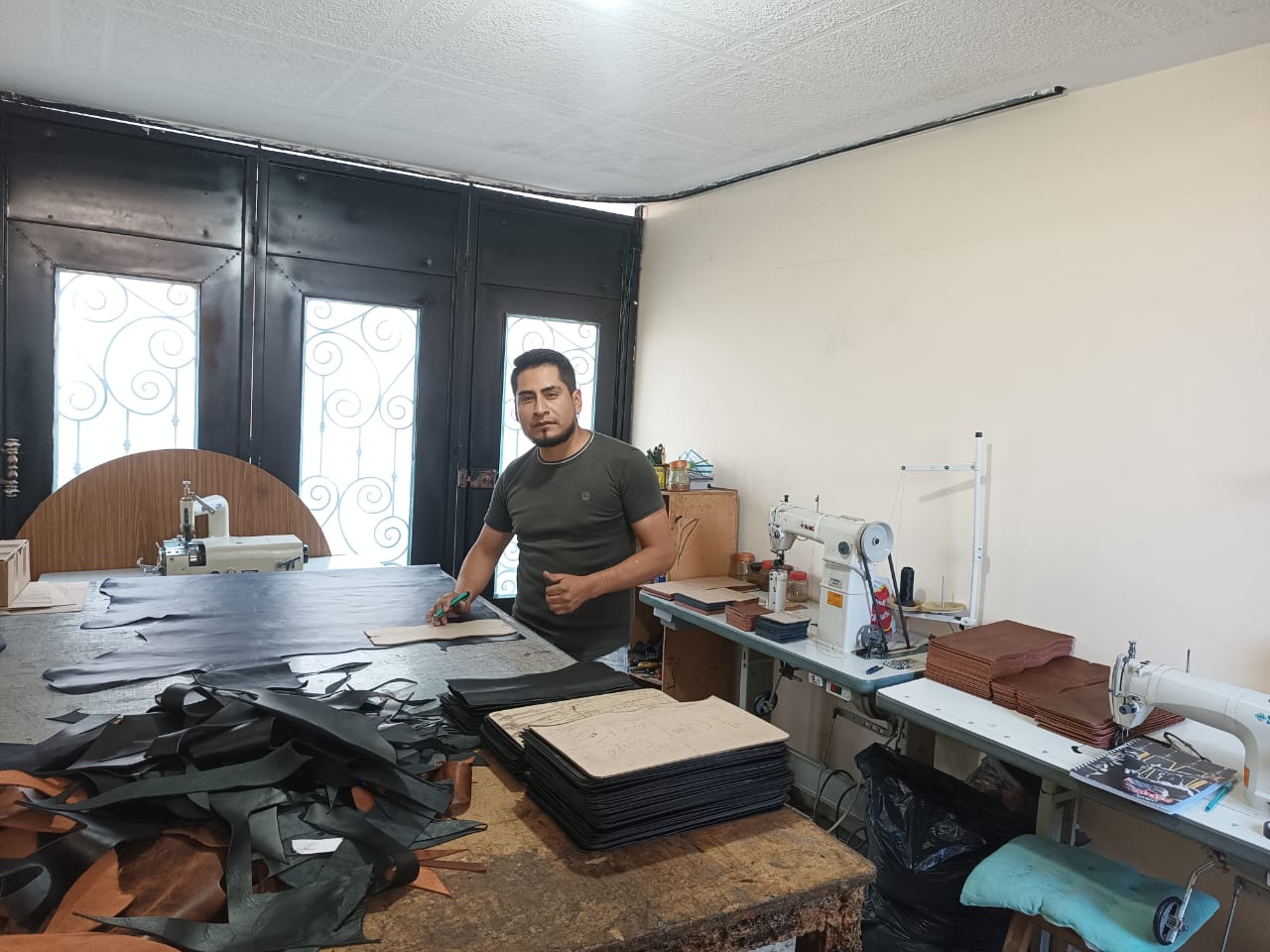 Man standing in a workshop with various tools and materials around him.