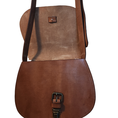 Brown leather bag with a strap on a wooden surface