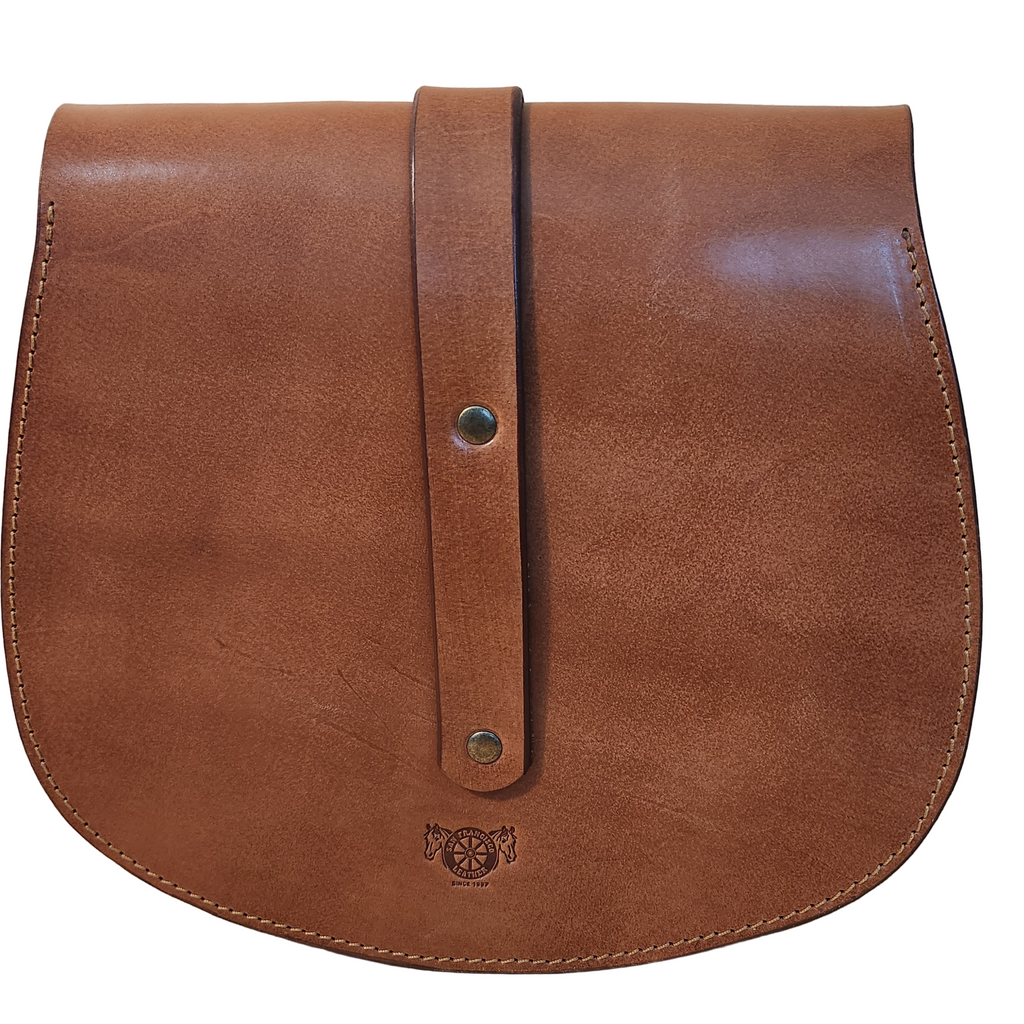 Brown leather bag with strap on a wooden surface