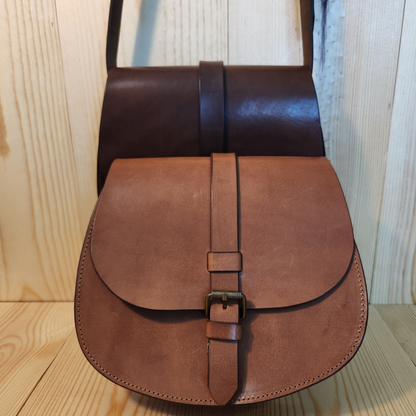 Brown leather bag with a buckle on a wooden floor