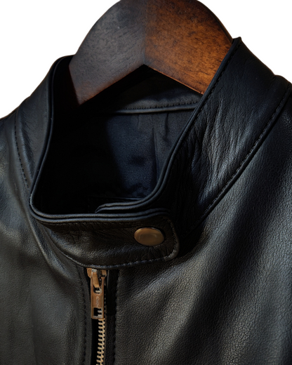 Black leather jacket on a wooden hanger against a blurred background