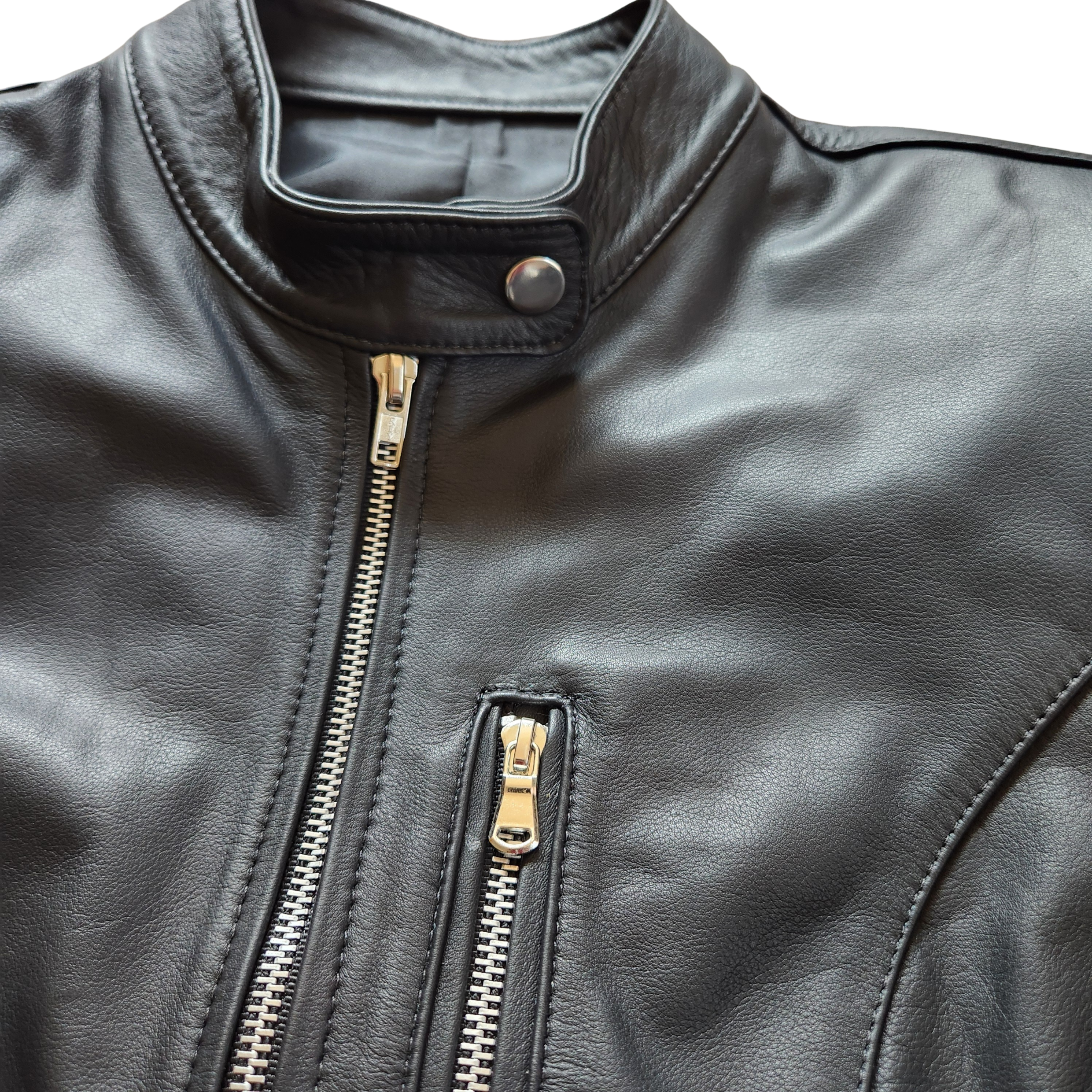 Close-up of a black leather jacket with gold zipper details on a white background