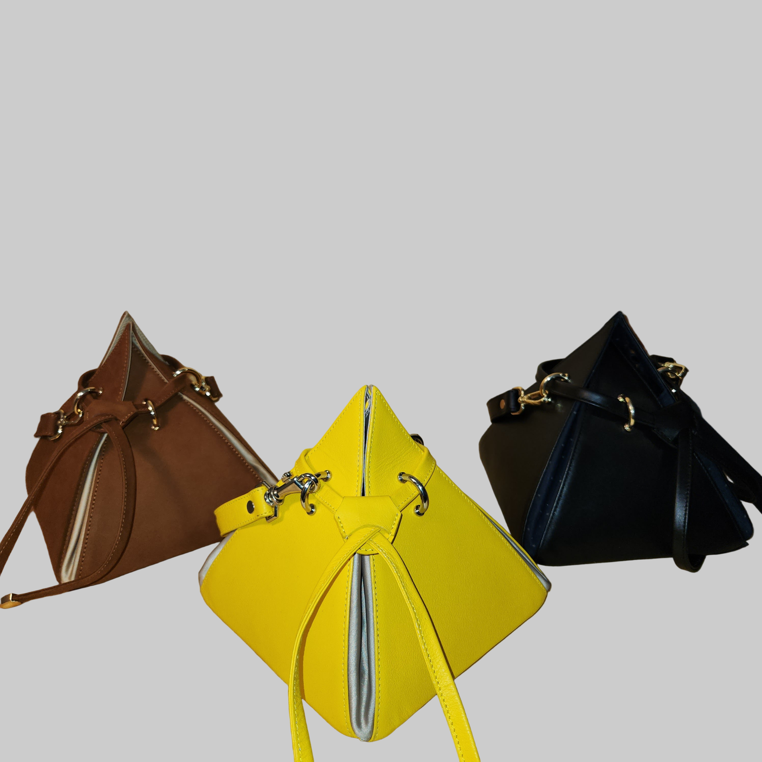 Three handbags in brown, yellow, and black on a wooden surface.