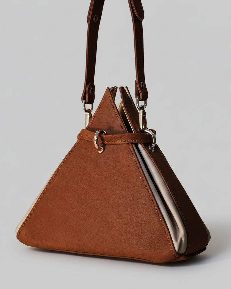 Brown triangle-shaped handbag with a strap on a wooden surface