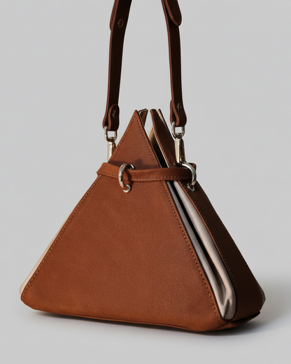 Brown triangle-shaped handbag with a strap on a wooden surface