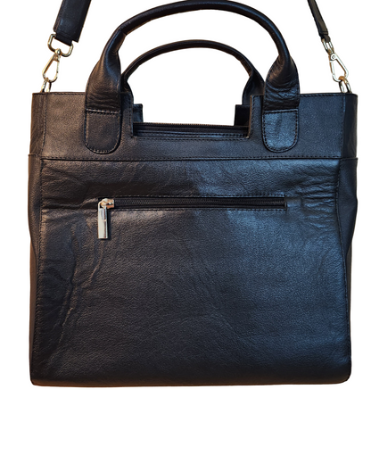 Black leather handbag with gold zipper on a wooden surface