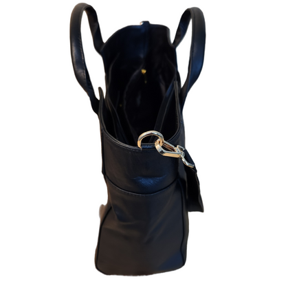 Black leather handbag with gold clasp on a wooden surface