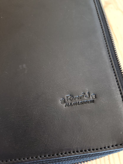 Close-up of a black leather product with a brand logo on a wooden surface