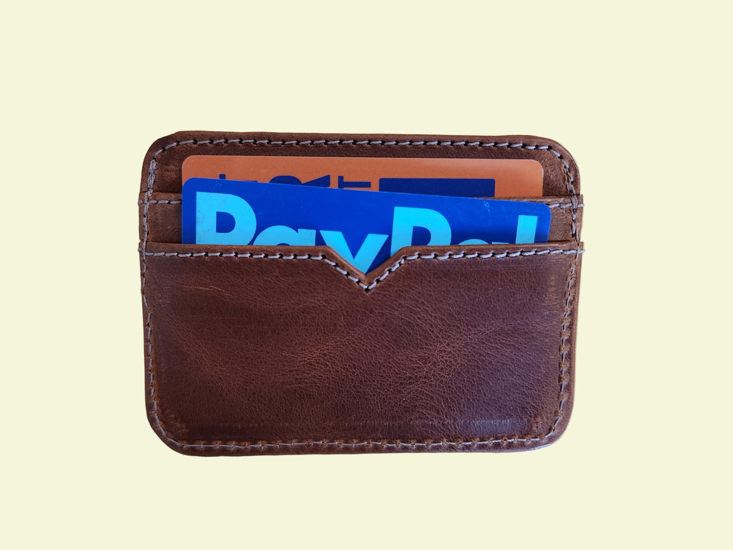 Brown leather wallet with colorful cards on a wooden surface